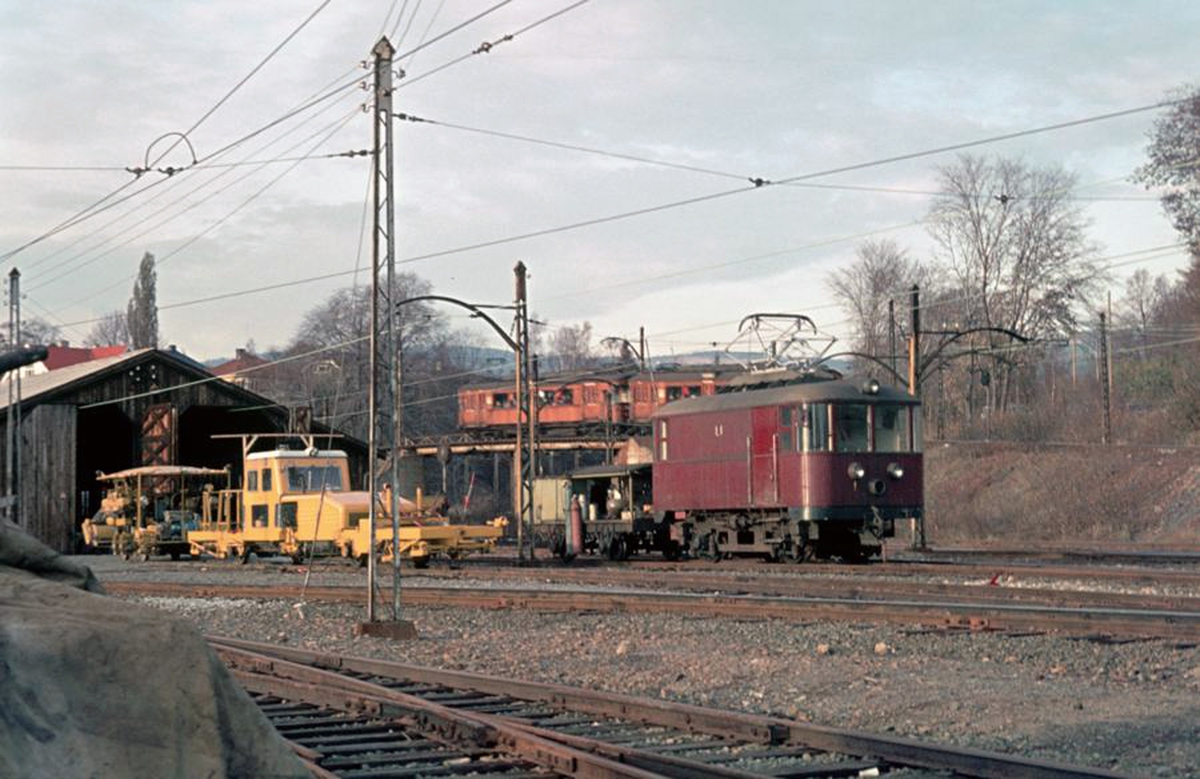 A/S Holmenkolbanen. Majorstuen vognhall-område. Baneavdelingen. HKB elektrisk lokomotiv L1 med sveisetralle, og pakkmaskin. I bakgrunnen vogn 611 og 612, type 1952, på vei mot Østerås.