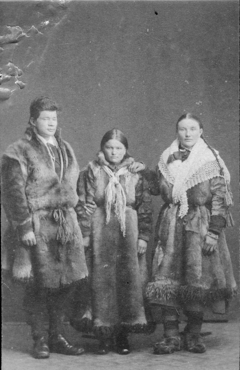Gruppeportrett av en mann og to kvinner, alle tre kledd i pesk