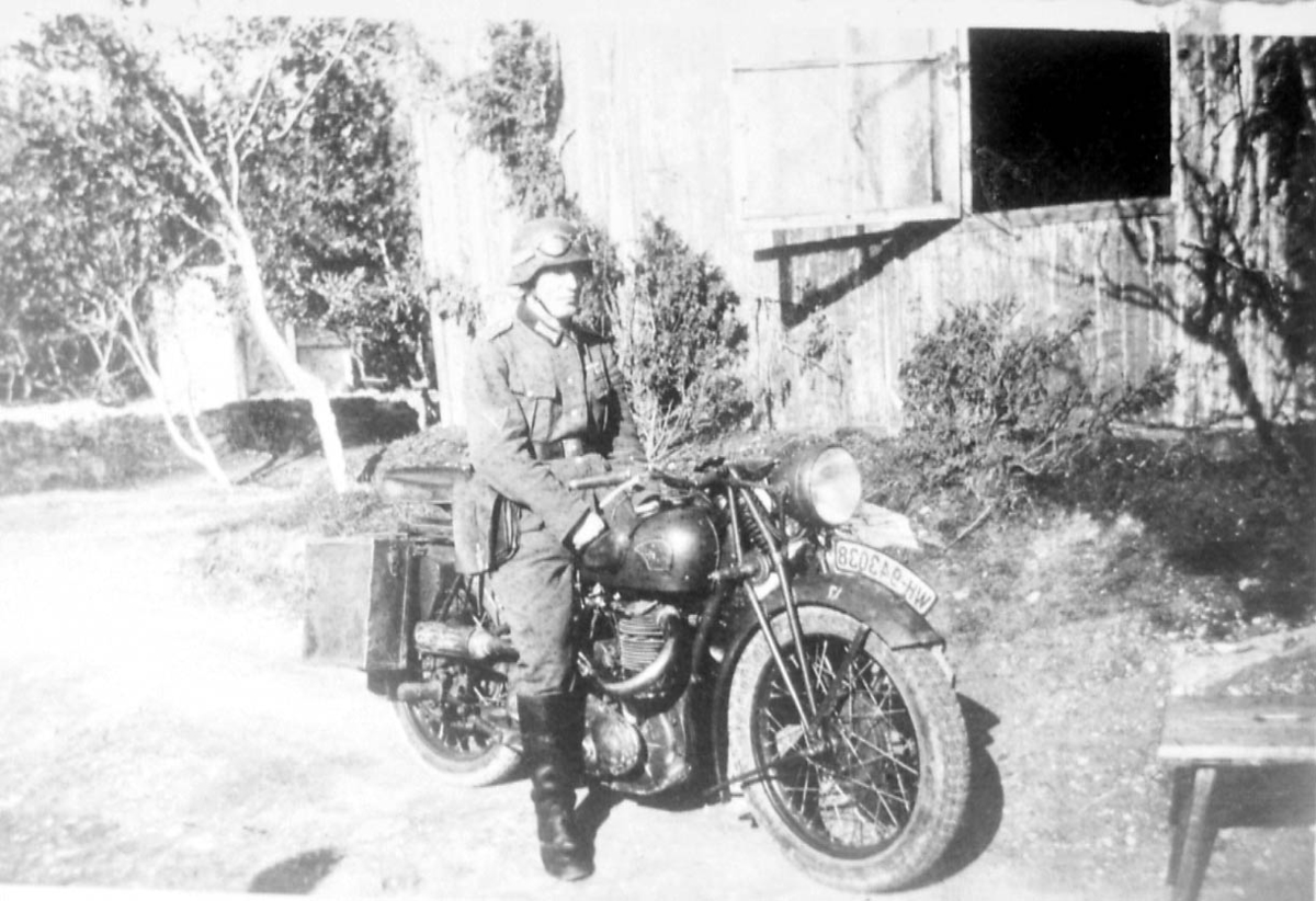 Portrett. 1 person, mann i militæruniform på motorsykkel, en tyskprodusert NSU. Sideveskene og selvsagt sjåføren, viser at dette er en militær utgave av NSU. .