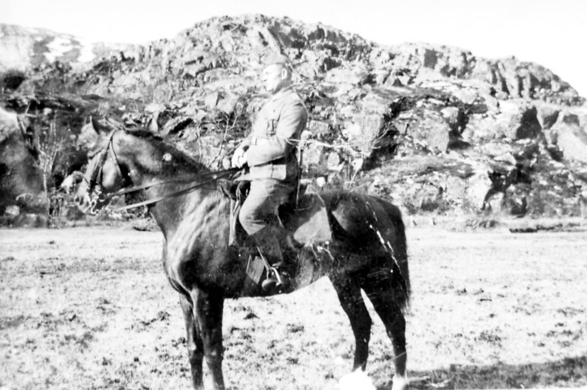 Portrett. 1 person, mann i militæruniform sitter på hesteryggen. Utendørs.