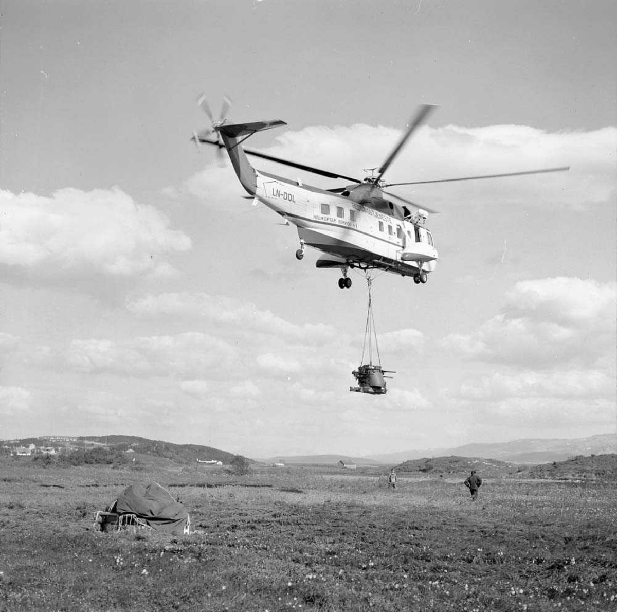 Et helikopter, Sikorsky, S-61, med kjennetegn LN-OQL, fra firmaet Helikoptertransport flytter luftvernartilleri-utstyr i forbindelse med øvelse "Barbara 8". Transporten skjer på Bodø flystasjon.