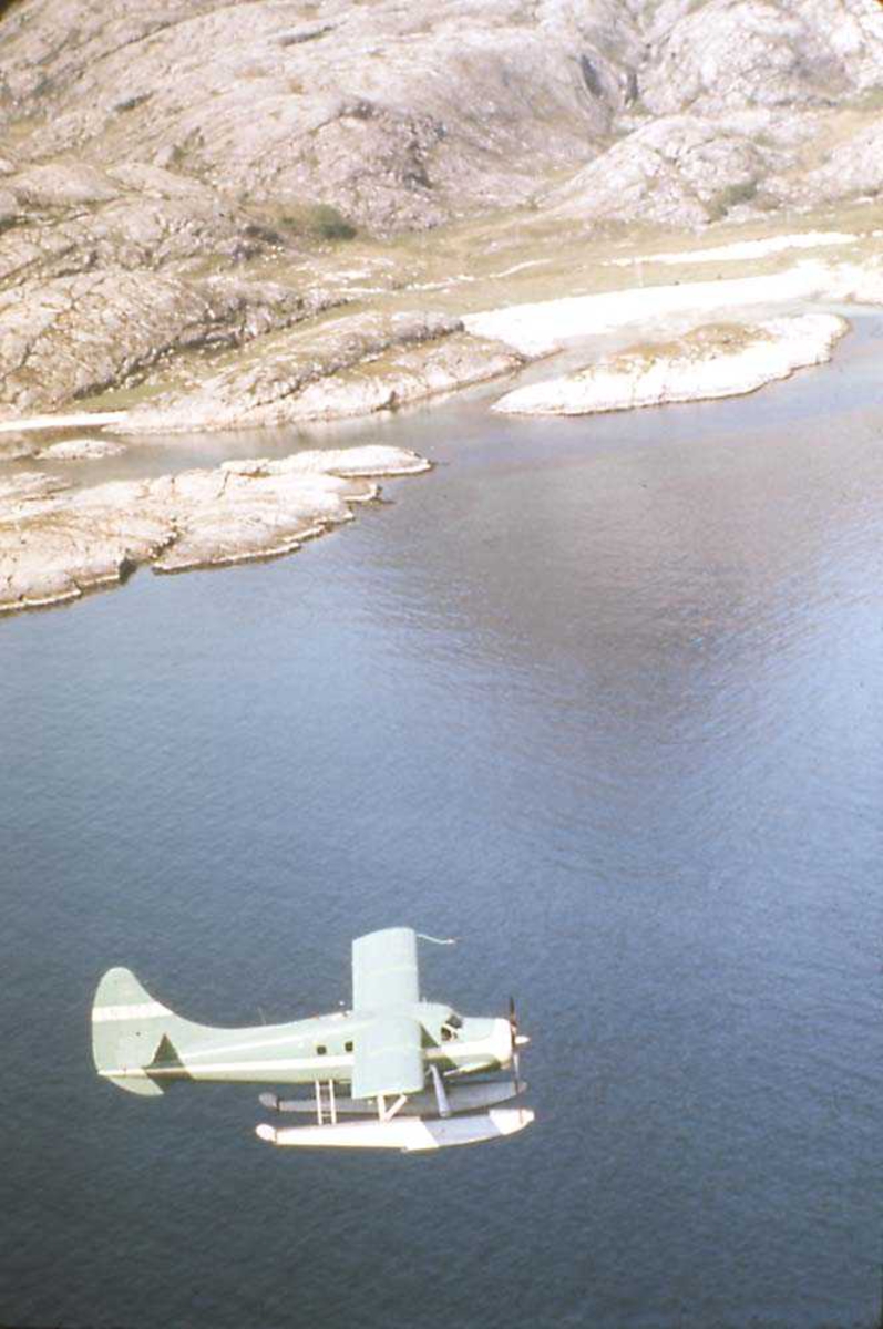 Luftfoto. Ett fly i luften, DHC-3 Otter LN-BDD fra Widerøe.
Fjell i bakgrunnen,