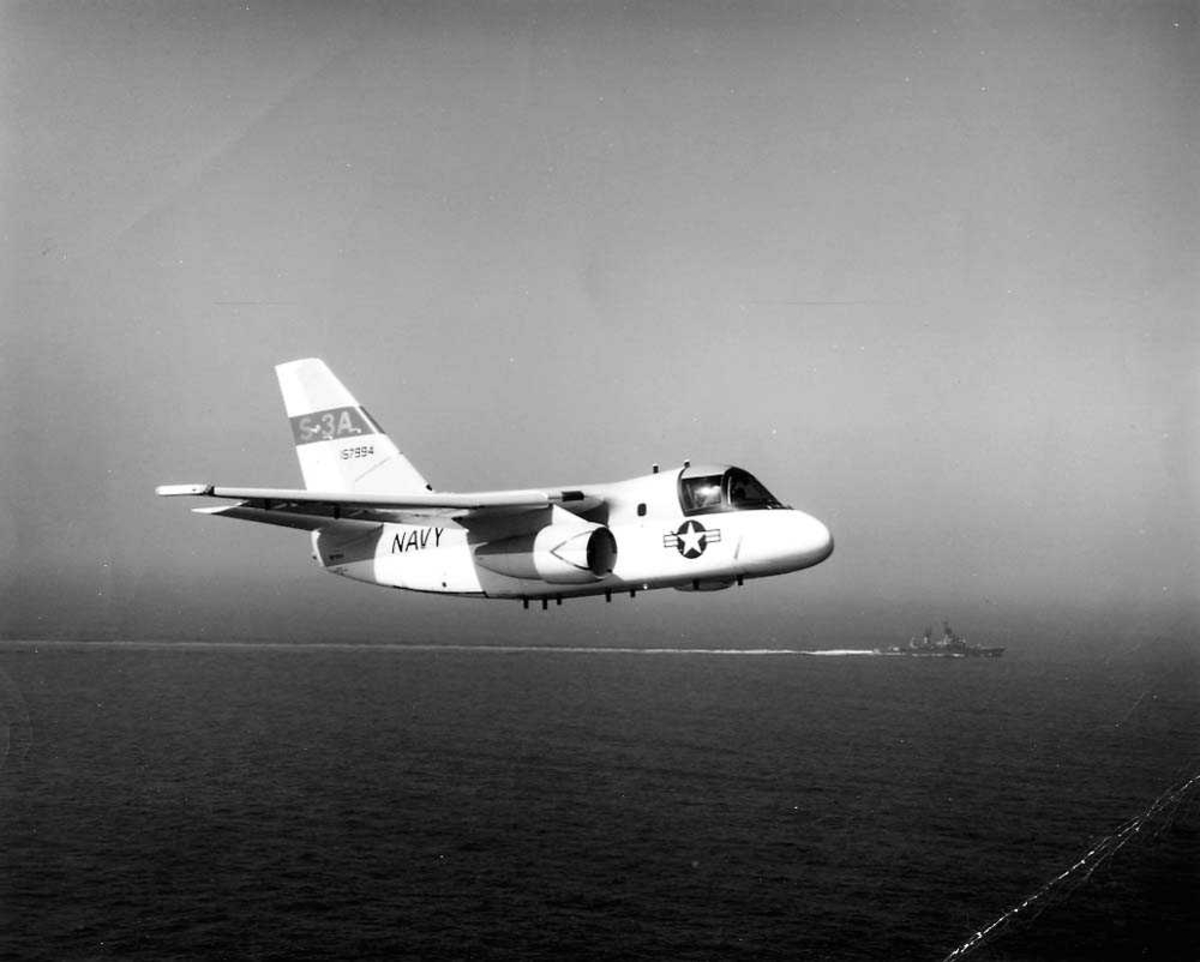 Luftfoto. Ett fly i luften, Lockheed S-3A Viking. Ett skip på vannet i bakgrunnen.