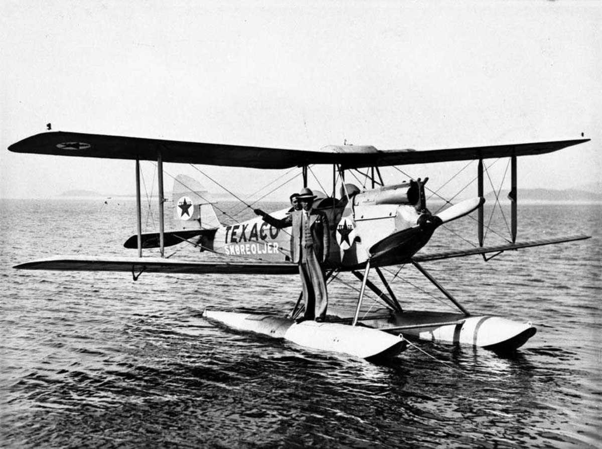 Ett fly ute på vannet, DH-60 Moth M fra Widerøes Flyveselskap.
En personer står på den ene flotøren til flyet, en person i cockpiten.