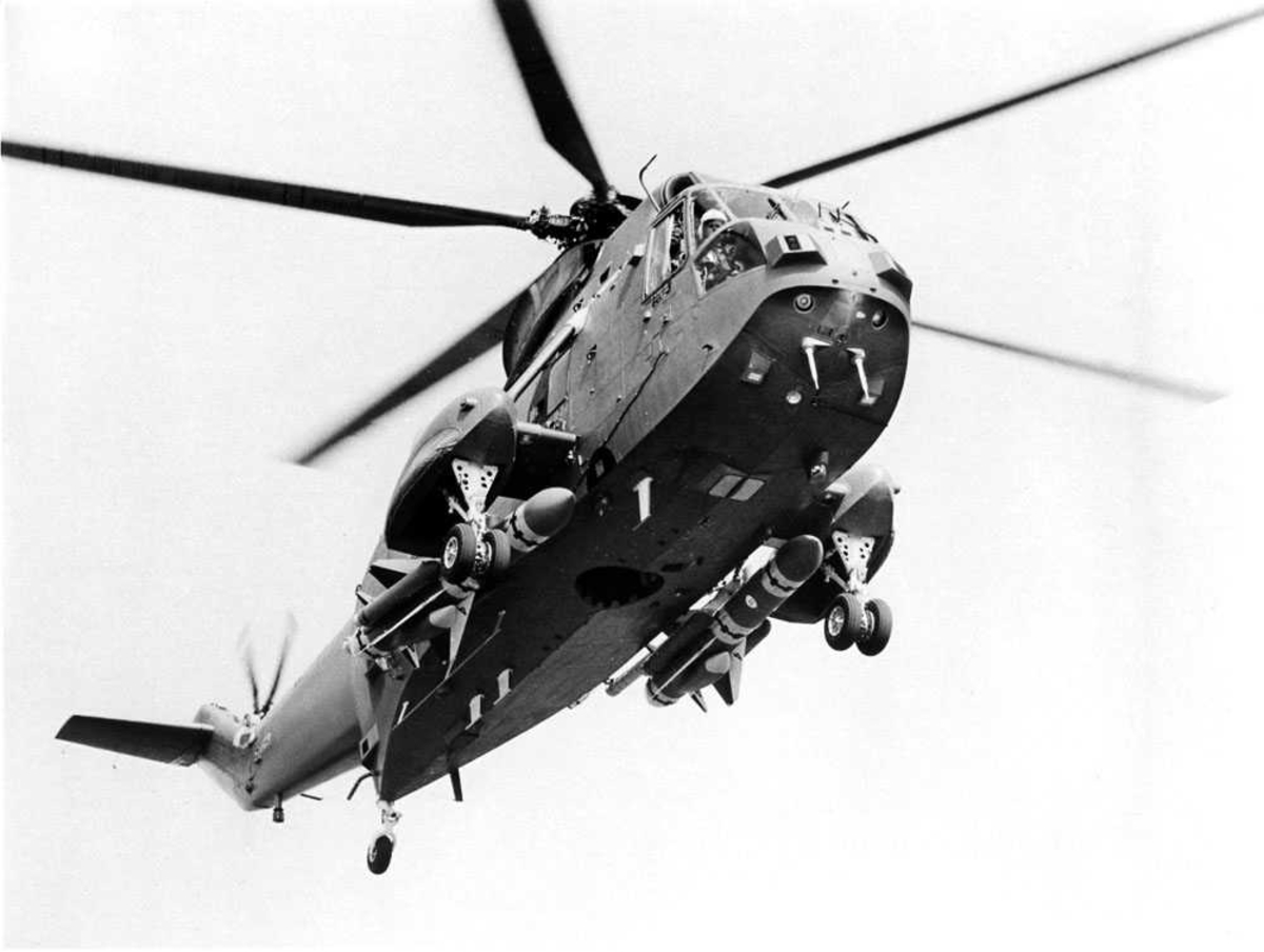 Ett helikopter i luften. Westland Advenced Sea King. To missiler ( BAe/UK Sea Eagle) hengende på hver sin side innenfor understell.