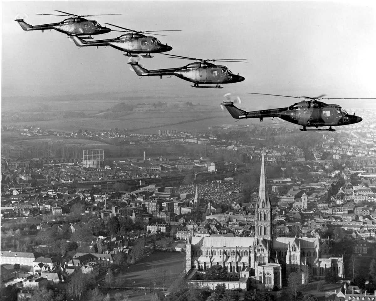 Fire helikopter i luften, i formasjon, over by. Westland Lynx AH Mk. 1 merket (topp ned) XZ170 XZ171 XZ175 XZ173. Katedral ses t.h.