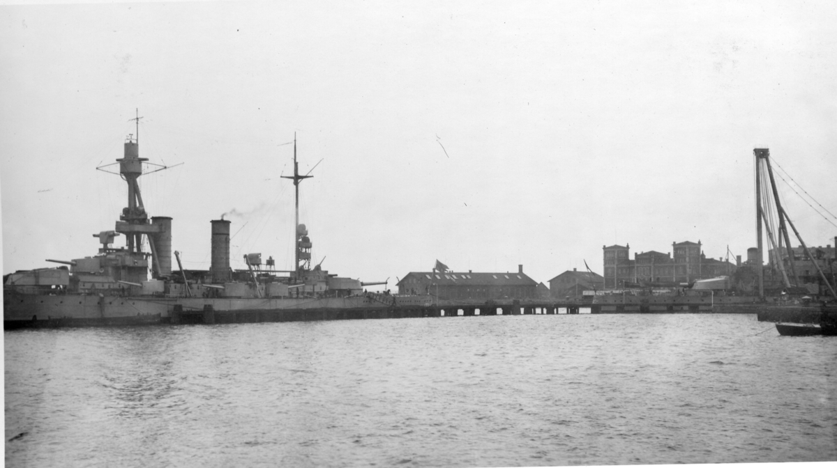 Pansarskeppet Drottning Viktoria vid utrustningspiren Pansarskeppet Gustav V i bakgrunden.