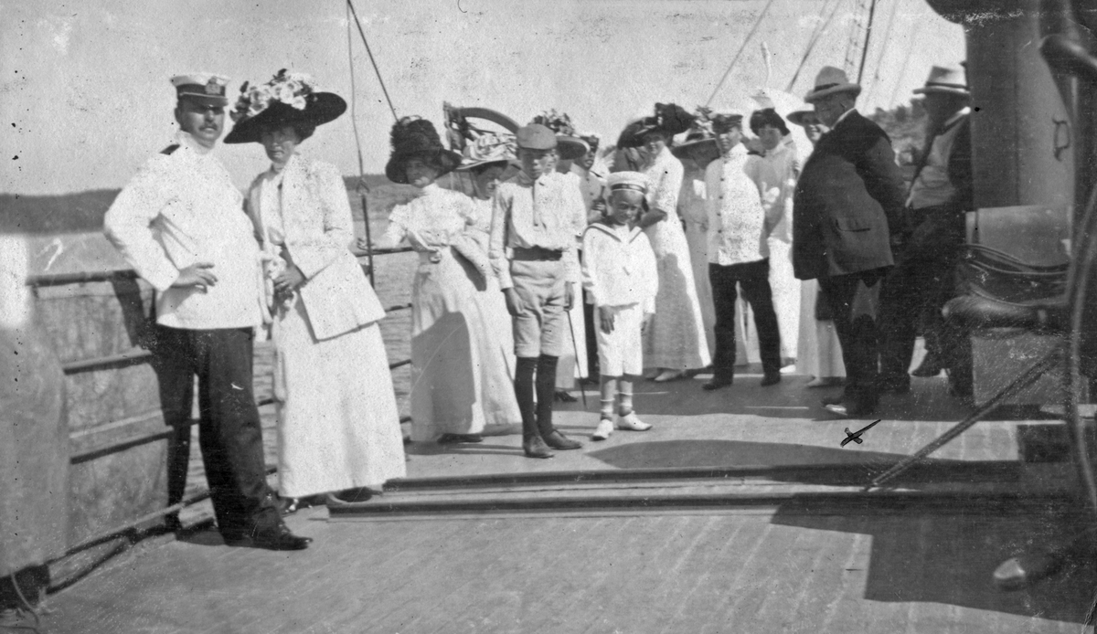 Party ombord på Blenda i Stenugnsund 1911. I bild syns finklädda damer i långklänning samt sjöbefäl i uniform.