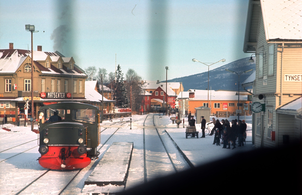 Tynset jernbanestasjon sett fra lokomotivet i Ht 301 (Dagtoget). Skiftetraktor type 214 i spor 2. Reisende venter på plattformen, og utvendig stasjonspersonale står klar med reisegods.