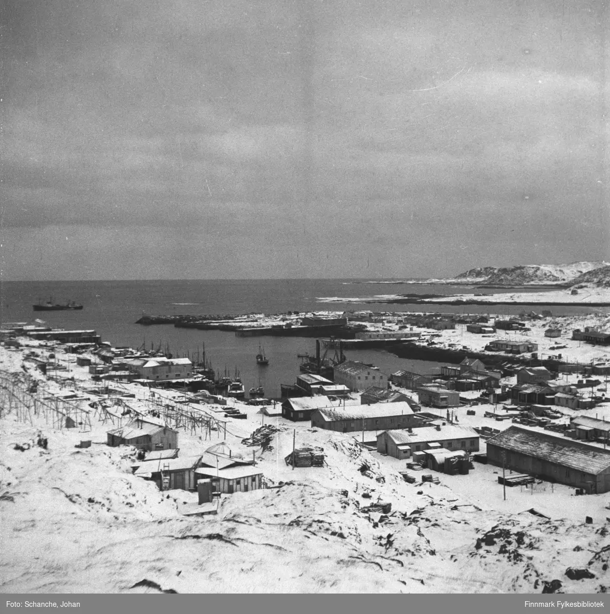 Oversiktsbilde over Berlevåg i gjenreisningstid.  På bildet ses nesten hele byen slik den var 1948. Bildet er tatt fra fjellet.  Noen båter ligger ved kai, et skip lengre ut i havet.  Samme motiv som i FBib. 95066-075.