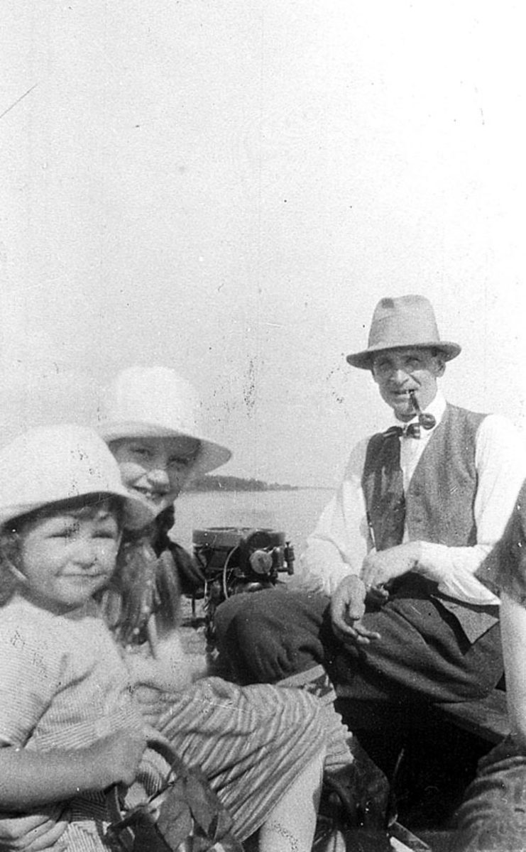 En man med pipa i munnen och två kvinnor i motorbåt.