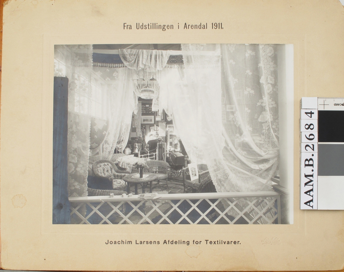 Utstilling, Joachim Larsens stand i Arendalsutstillingen 1911 , interiør med kurvstoler, bord, tekstiler m.m.