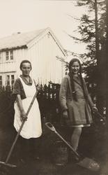 To ungjenter, fortografert utendørs med spader og hageredska