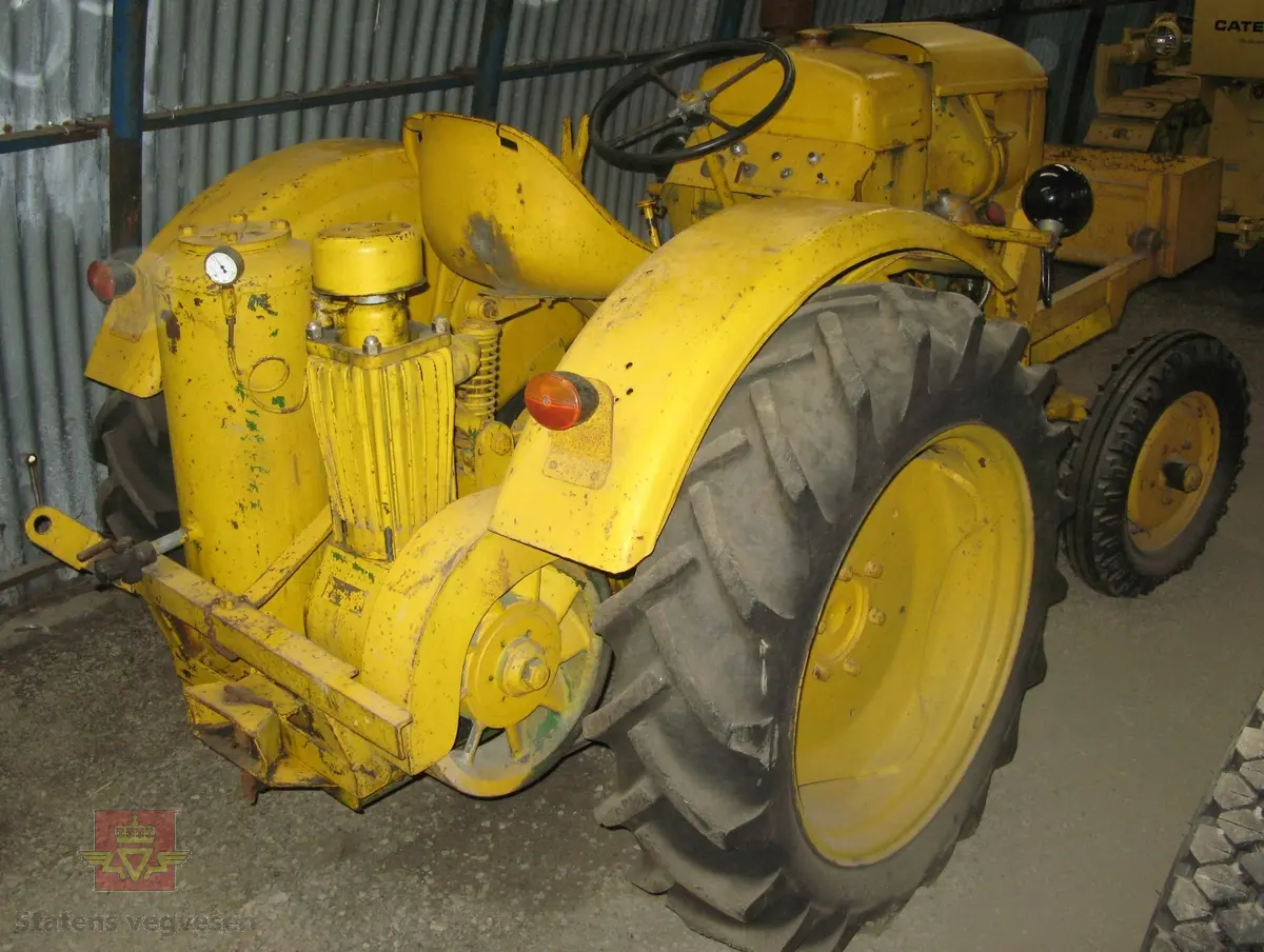 Kløckner-Humbold-Deutz type: F1L 514/51. Traktor, gul, uten førerhus, med 4 gummihjul. Kasse påmontert foran og luftkompressor bak. Motoren er dieseldrevet, ensylindret med en ytelse på 15 Hk. Merket av produsent og forhandler.