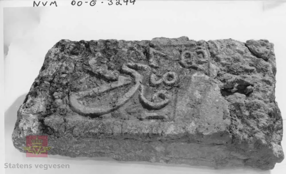 Kalkstein med inskripsjon: "UFG 1687". Noe av monogramet er borte. Steinen er brukket, øvre del mangler.