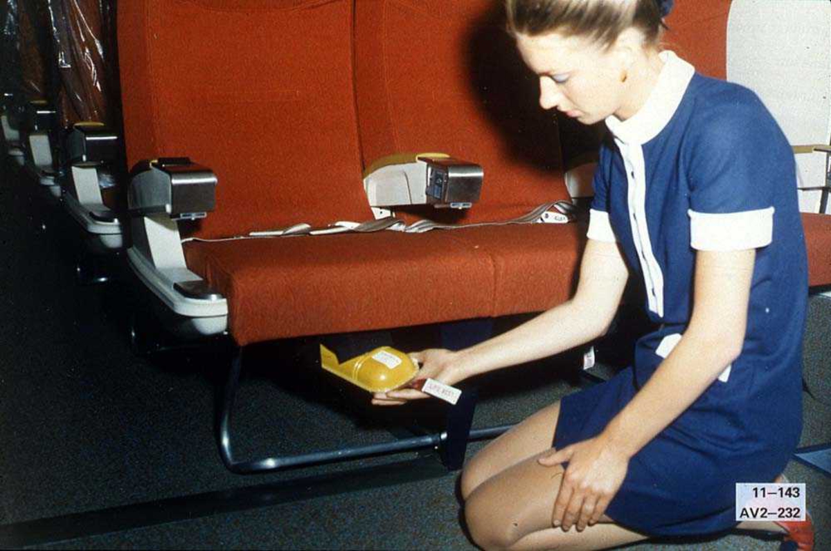 En person som sitter foran noen seter inne i kabinen på et fly, Boeing 737-200.