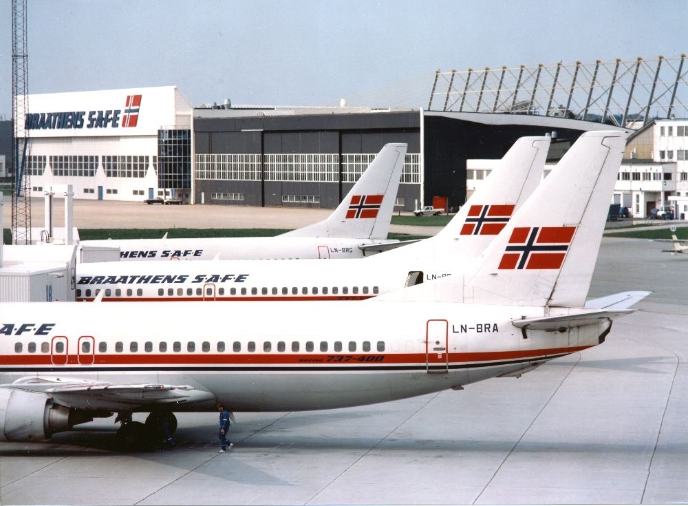 Lufthavn/flyplass.  Tre fly, Boeing 737 fra Braathens SAFE, oppstilt på parkeringsplass (tarmac). I bakgrunn Baathens SAFE's tekniske avdeling.