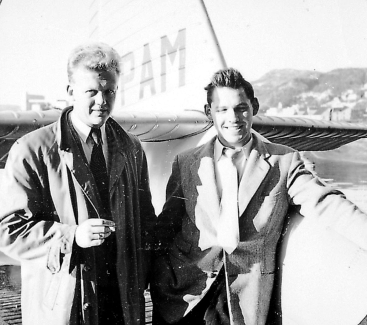 Portrett, 2 personer på ei kai. 1 fly,  merket PAM, ligger ved kaia  