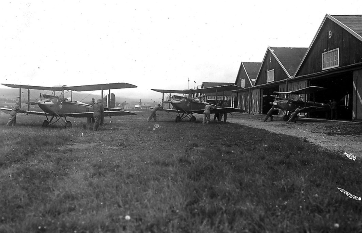 Kjeller lufthavn, flere personer flytter  tre De Havilland DH. 60M Gipsy Moth  inn i en hangar.
