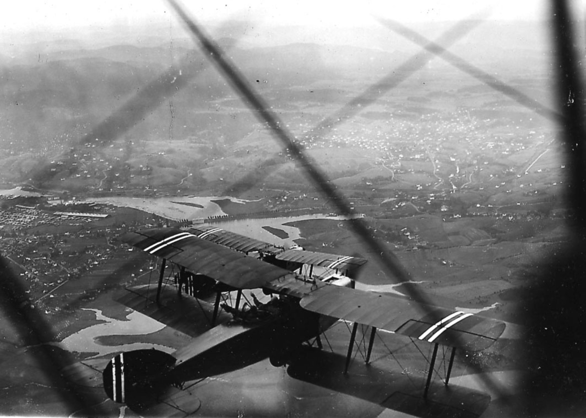 Luftfoto, to fly i luften, Bristol Fighter. Landskap under. Stag og vinge på ett fly, hvor bildet er tatt fra, i forgrunnen.