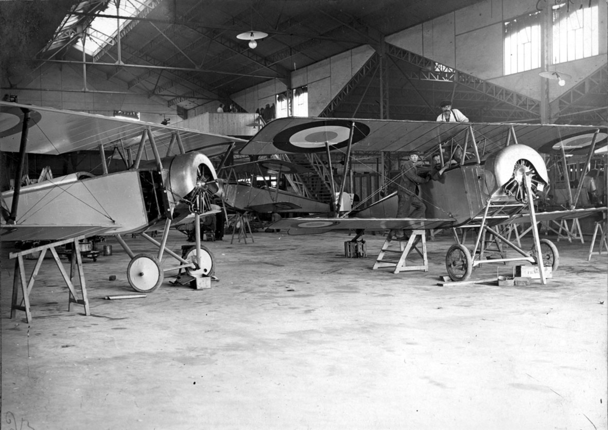 Fly, 2 stk. Nieuport 11C.1, inne i hangar. Noen personer arbeider på flyene. 