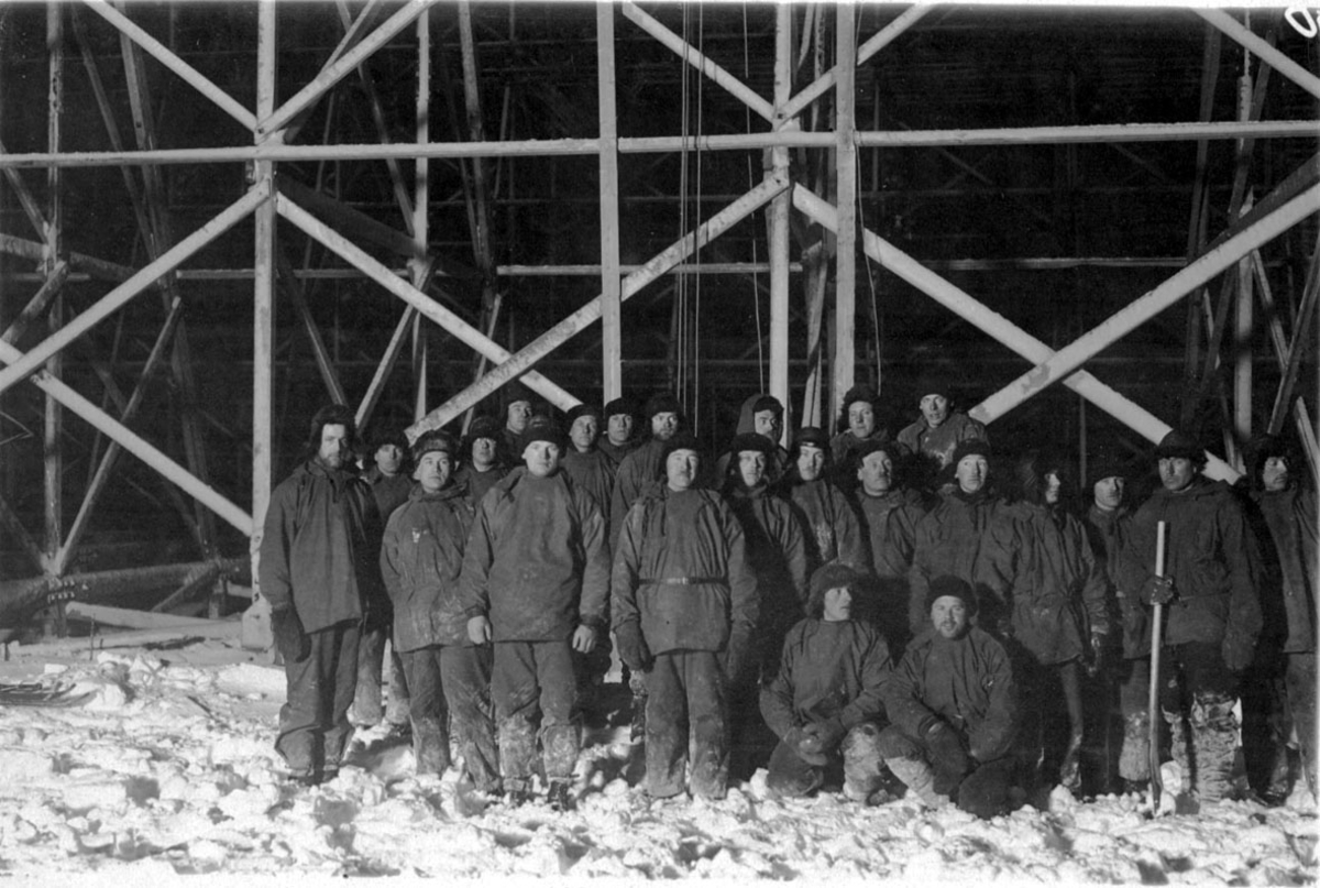 Flere personer oppstilt inne i lufskipshangaren, arbeidslaget. Hangaren er ferdig, men ikke tømt for snø.