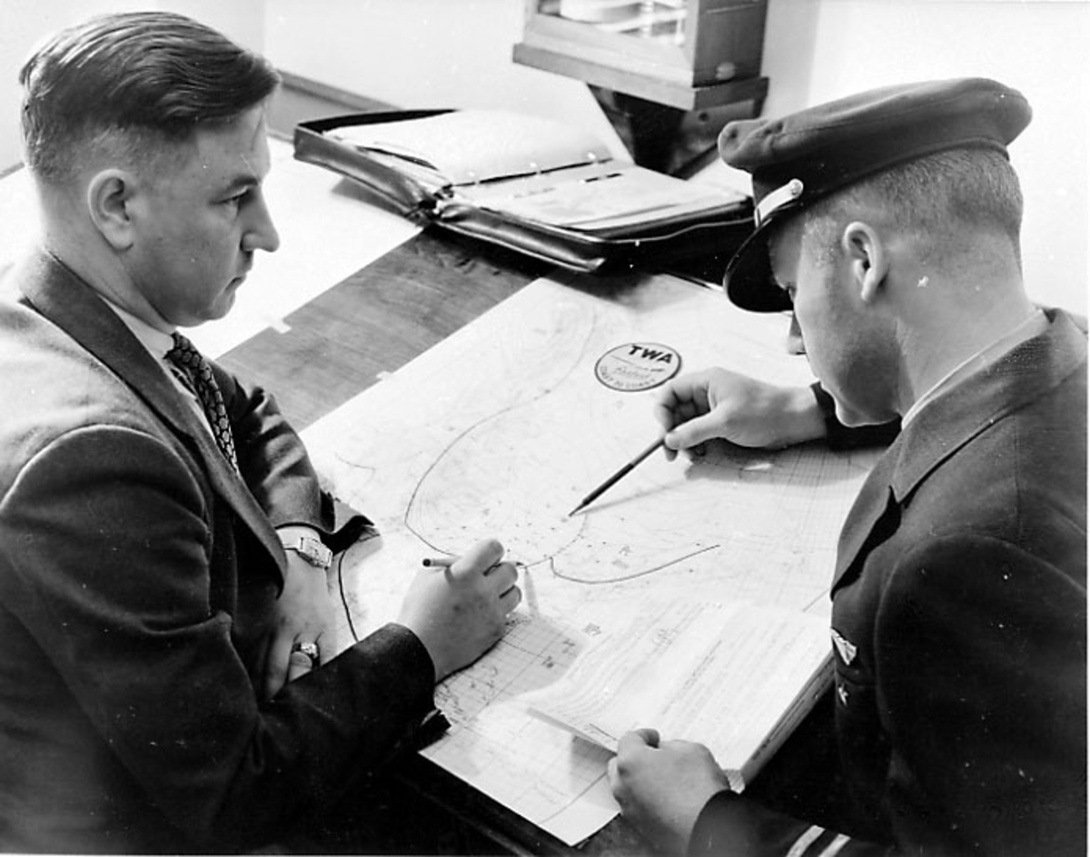 Div. reklame og opplysninger om TWA - illustrert med bilder, skisser og tekst. 2 personer studerer et kart - flyrute.
