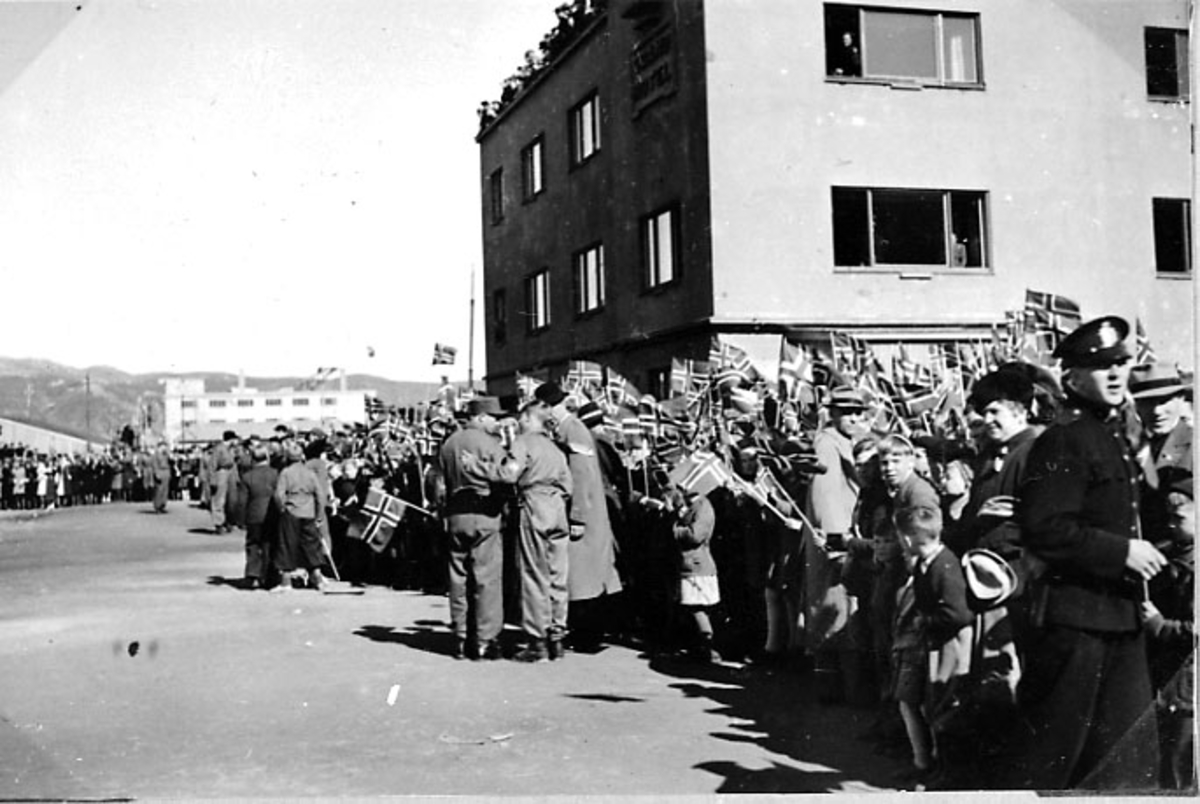 By, store folkemengder i gatene med norske flagg. Grand Hotell bak.