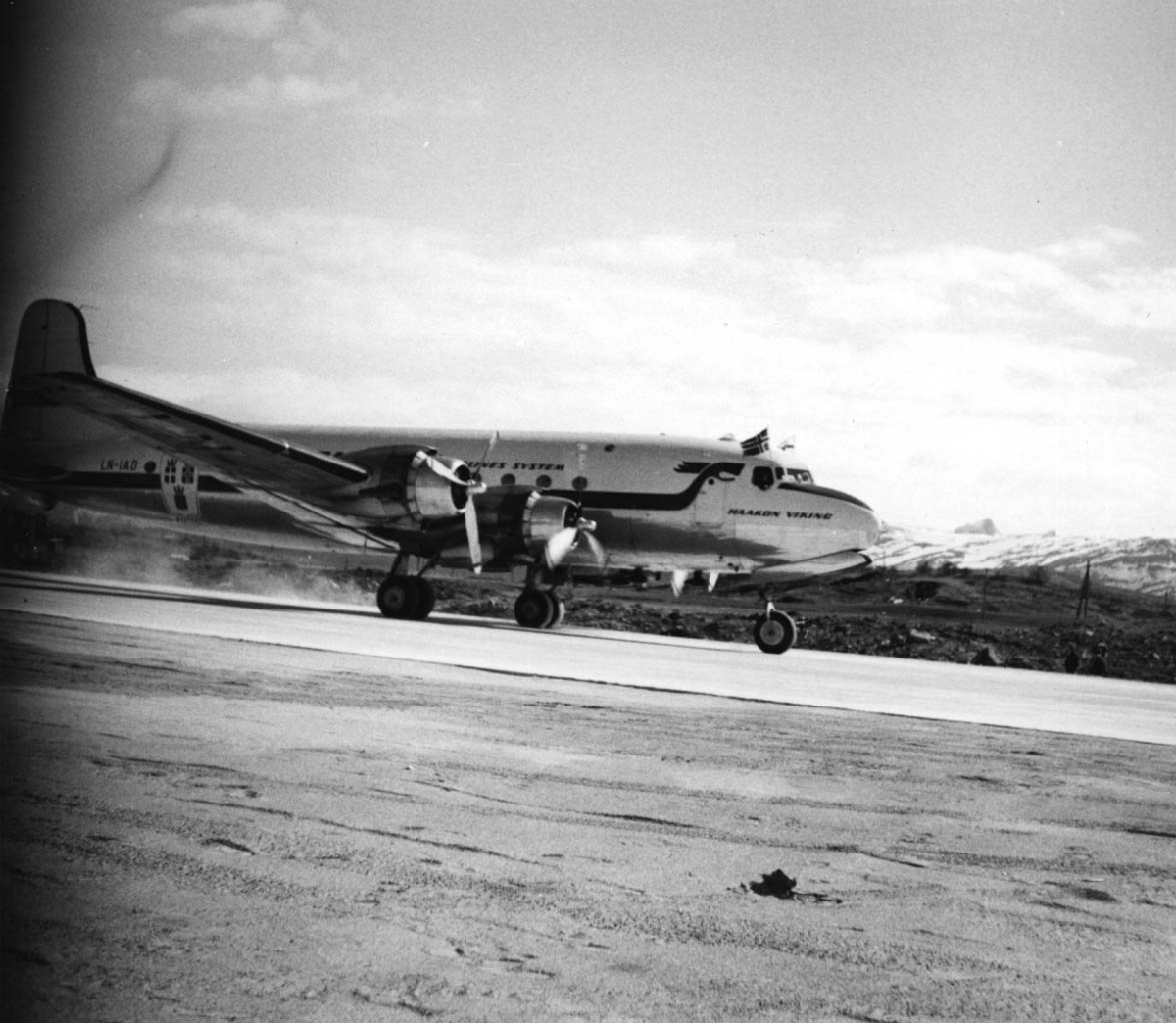 Lufthavn, 1 fly på bakken, Douglas DC-4 /C-54-1009 Skymaster. Mil C-54 LN-IAD "Haakon Viking fra DNL/SAS. Flere personer ved flyet.