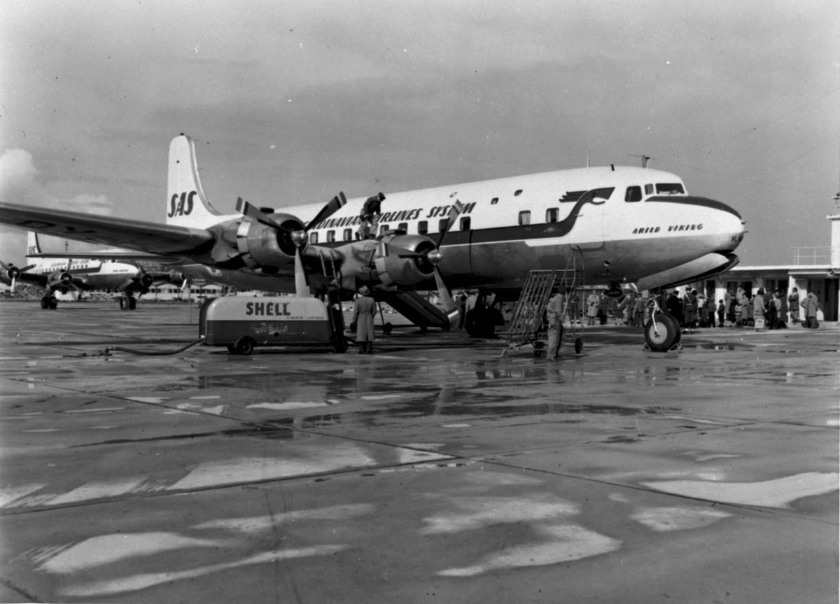 Lufthavn, 1 fly på bakken, Douglas DC-6 OY-KM? "Arild Viking" fra SAS. Flere personer - passasjerer ved flyet.