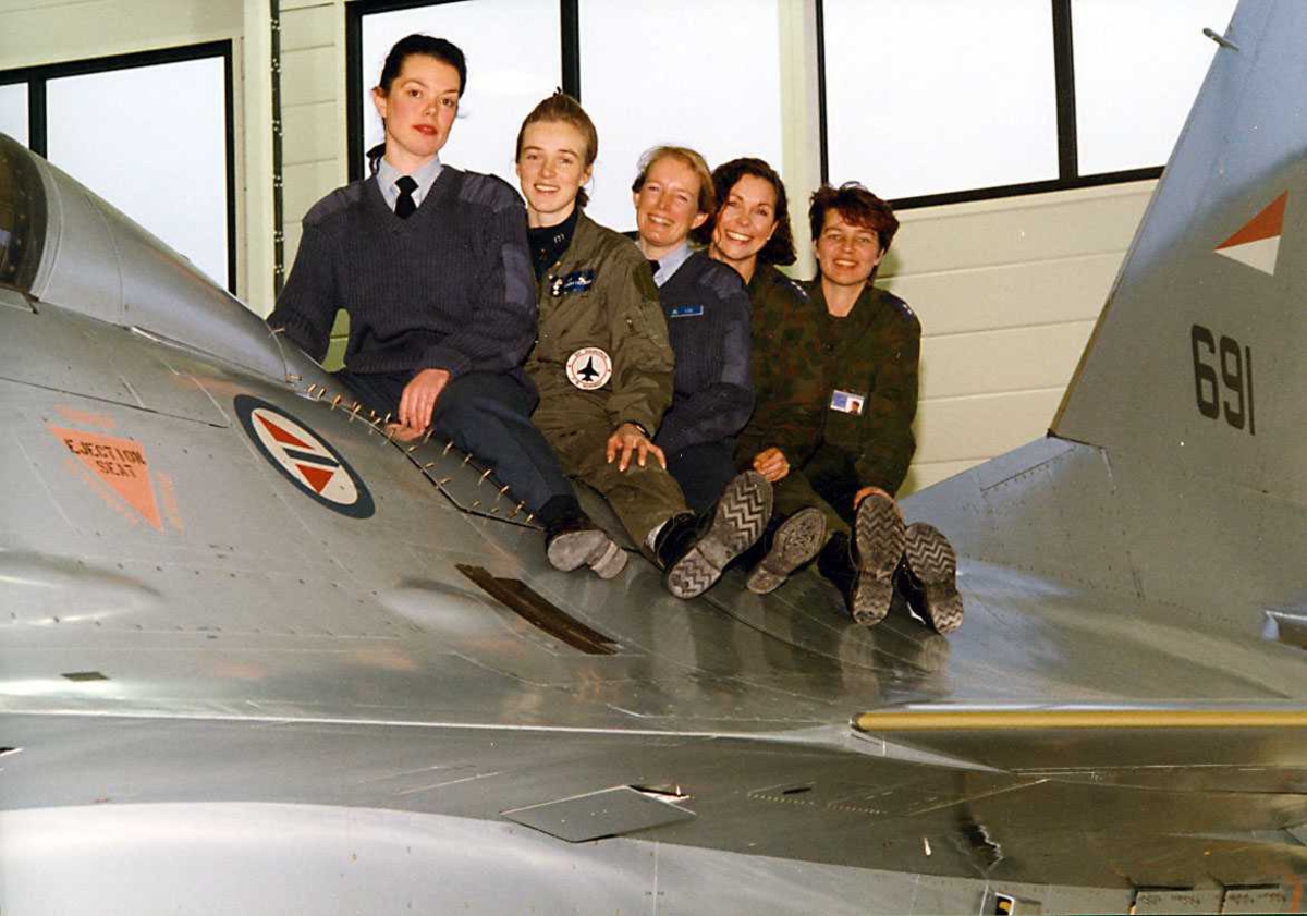 Gruppe.   Fem kvinnelige offiserer sitter på en F-16.