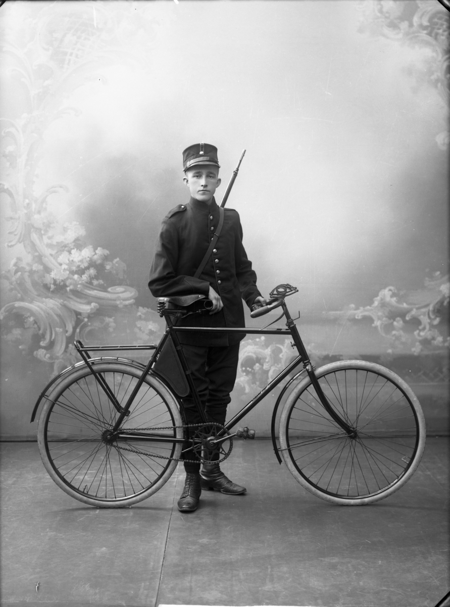 En ung mann i uniform med sykkel fotografert
