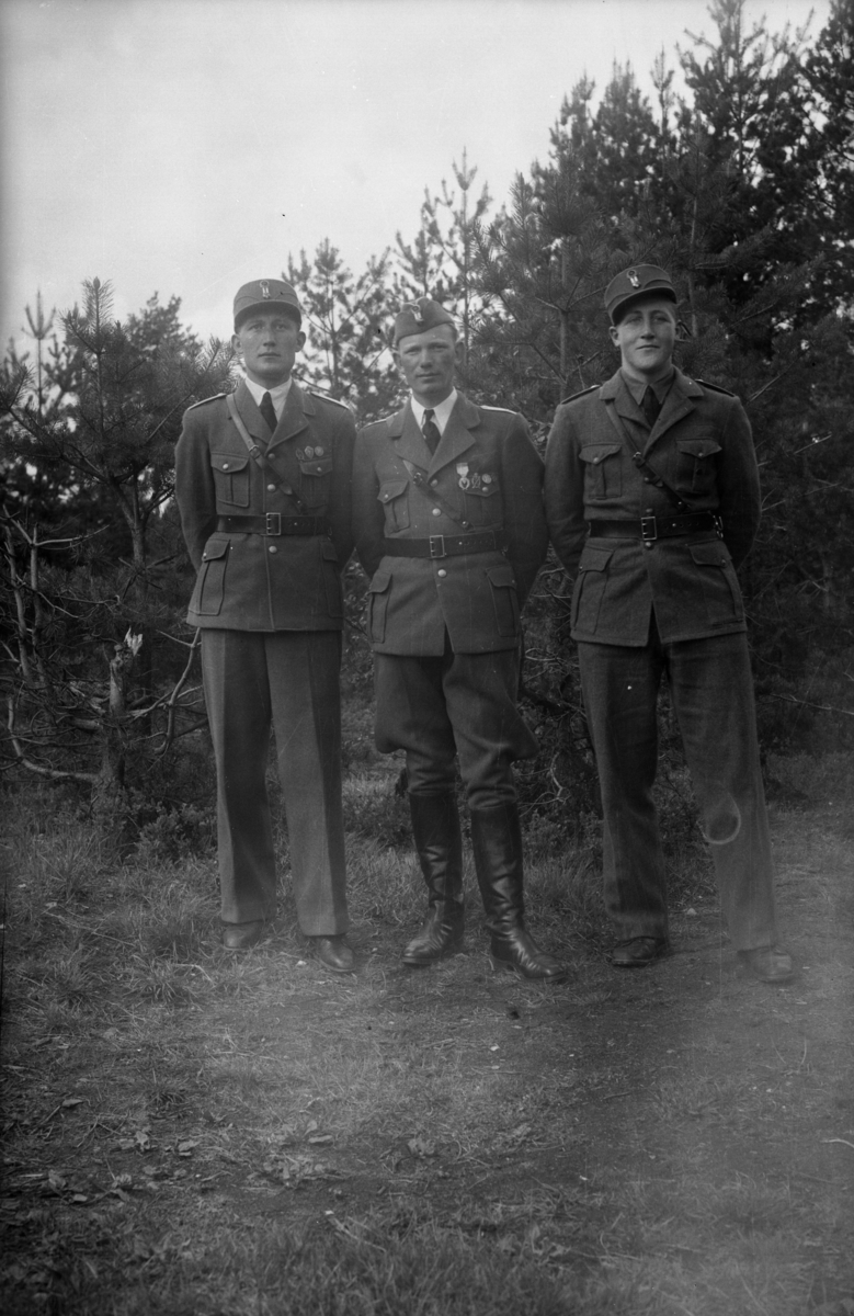 Tre unge menn i uniform fotografert utendørs