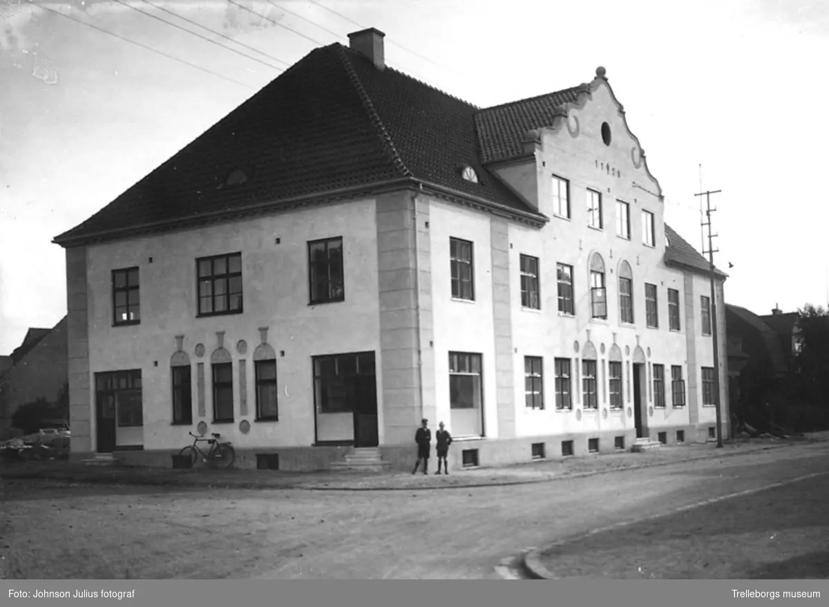 Trelleborgs Allehandas egen härd, J. Hanssons hus på J.W. Wulffsgatan 8 i kv Kapellhejdan år 1928. Hörnet av J W Wullfsgatan - Kraaksgatan. På bottenvåningen fanns en speceriaffär och en mjölkaffär. Senare innehades affären av Agardh Nilsson.