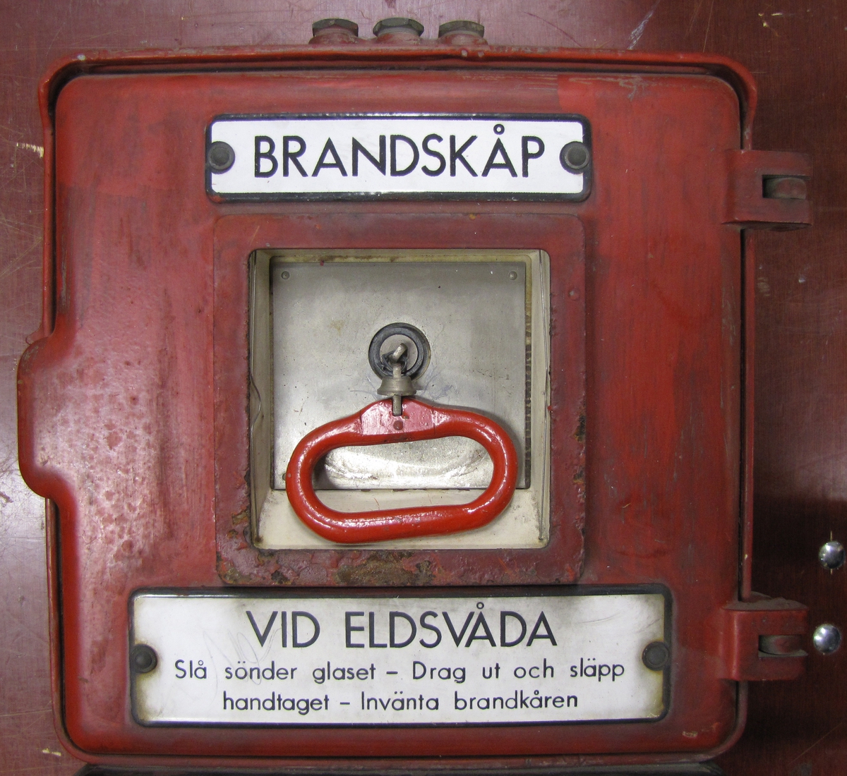 Brandskåp som varit placerat ute i staden (Vänersborg).

Vid eldsvåda: slå sönder glaset.
Drag ut och släpp handtaget.
Invänta brandkåren.