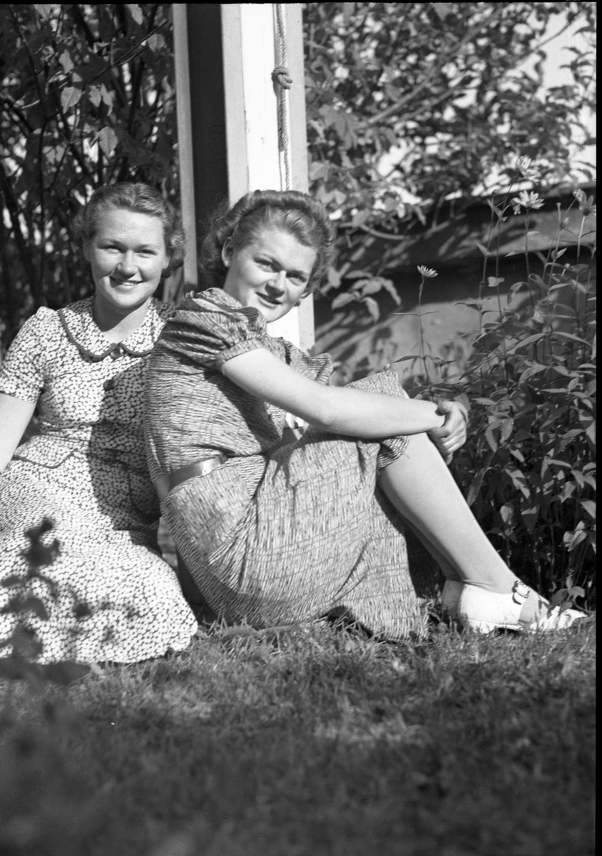 To kvinner i sommerkjoler i gresset ved en flaggstang. 1939