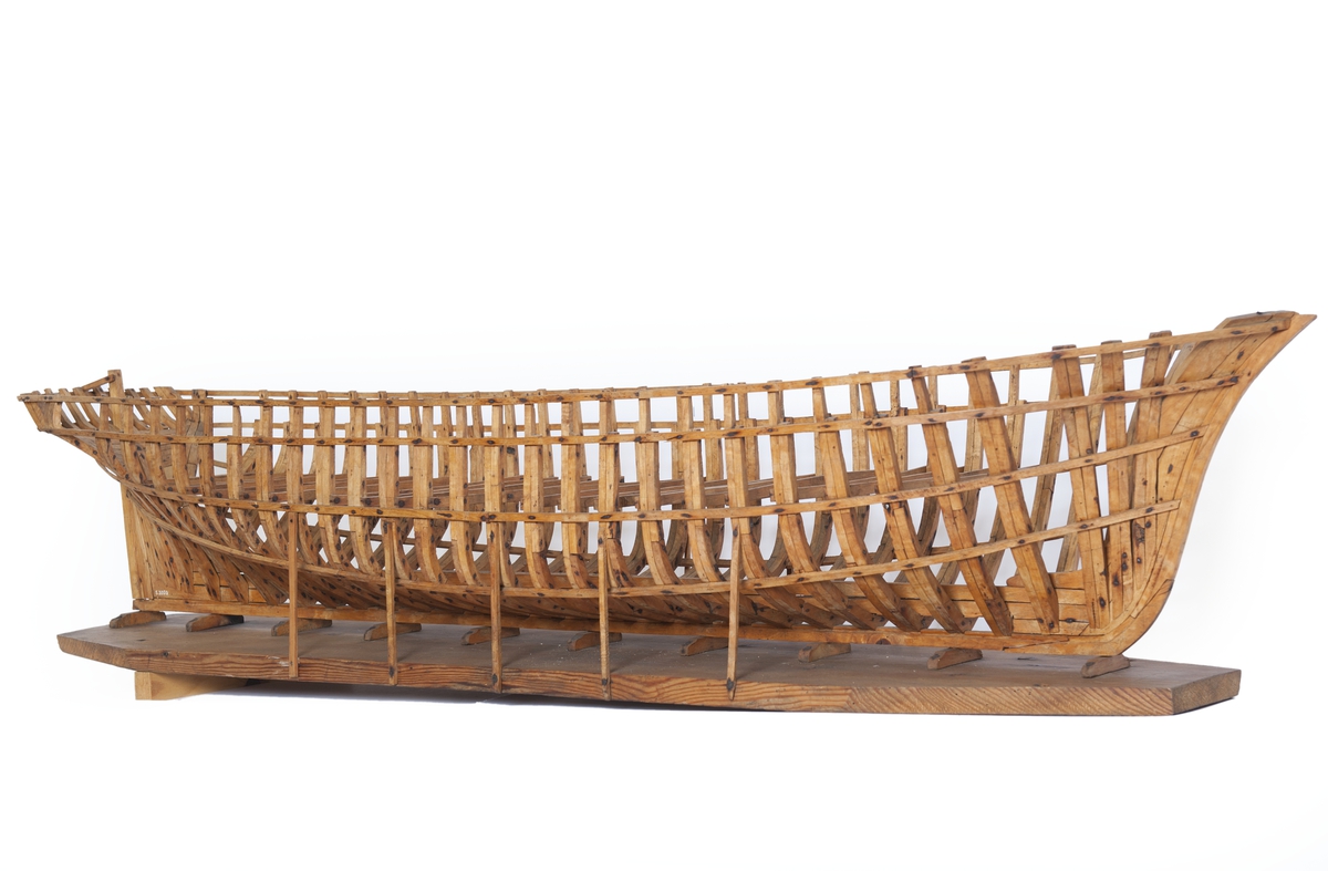 Fartygsmodell av ek, spantmodell till briggen "DAGMAR" av Uddevalla (1869). Spantbyggd utan bordläggning, stående på stapelbädd. Modellen monterad på en åttkantig platta av trä. 12 stöttor