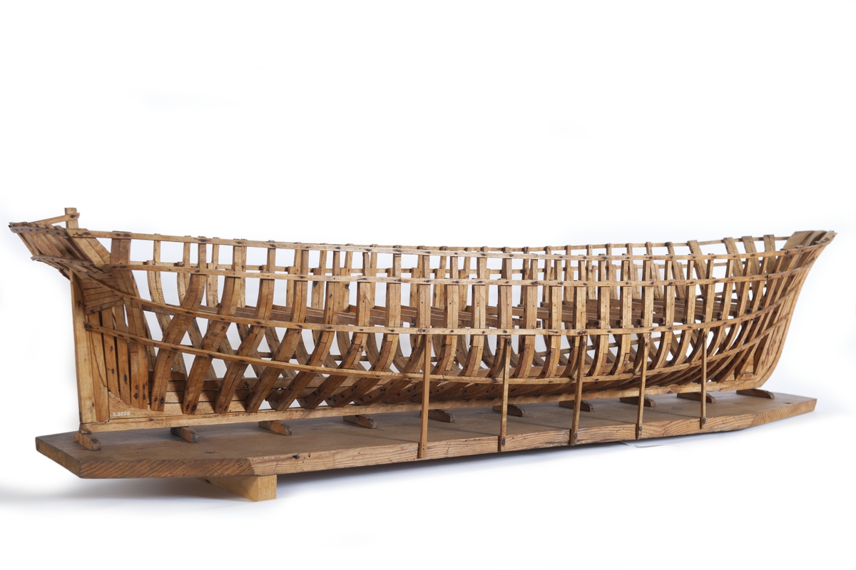 Fartygsmodell av ek, spantmodell till briggen "DAGMAR" av Uddevalla (1869). Spantbyggd utan bordläggning, stående på stapelbädd. Modellen monterad på en åttkantig platta av trä. 12 stöttor