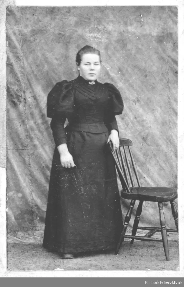 En kvinneportrett montert på lys rosa kartong. Kvinnen er Anna Særvold,  født 24.06.1876 i Vadsø. Hun er gift med Oluf Særvold, fisker,  født 14.04.1874 i Rødø, Helgeland. Bak bildets kartong er det notert "Fra Anna til Nanna Balo".  Fotografen er ukjent. Anna er kledt i en svart kjole,med bluseliv med puffermer og et langt svart skjørt. I halsen har hun en liten nål.  Bildet er tatt med en litt provisorisk bakgrunn, kanskje et seil fra en båt og en pinnestol - og kjolen kan være brudekjole, sort brudekjole var vanlig på den tiden. I albumet er det skrevet Servold, istedet for Særvold. Nanna Evida Bergitte Vara, født Balo (født 09.10.1878) er sannsynligvis den personen som Anna har dedikert bildet til. Nanna var gift med Paul Rudolf Vara, som drev med fiskeri. 

I folketelling for 1900 i Vadsø er hun registrert på adresse Thomas von Westensgade 4, 2.etasje. I 1900 har de en sønn, Casper Særvold, født  05.06.1900.
I folketellingen for 1910 er de flyttet til Vardø og bor i Kristian 4des gate 119. De er da registrert med 3 sønner, Odin (født 10.08.1901), Hans Herman (20.03.1905) og Gunnar (31.01.1909) Særvold. Anna er da registrert som Anna Lovise Særvold, fiskers hustru. Anna Lovise er registrert på sykehuset i Vadsø i 1910 "pasient paa sygehuset". Hvor det det er blitt av Casper Særvold vites ikke. Gunnar Særvold er i 1910 "bortsat til forpleining", han er da 1 år, mens Hans Særvold også er "pasient på Sygehuset".
