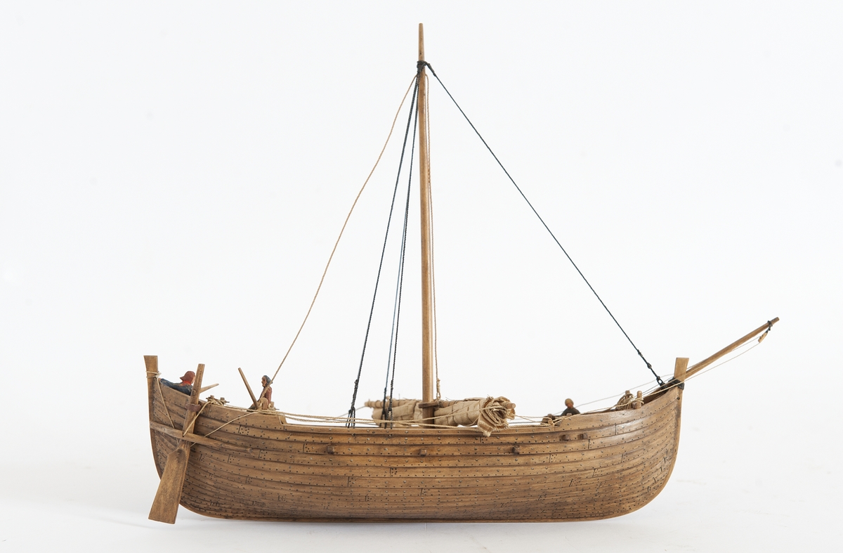 Fartygsmodell av oxelträ, rekonstruktion av Falsterbofyndet, från äldre medeltid. Skrov utfört i två halvor, limmade, bordläggningen skuren. Ankare med tåg och vakare. Träet betsat i tjärfärg.