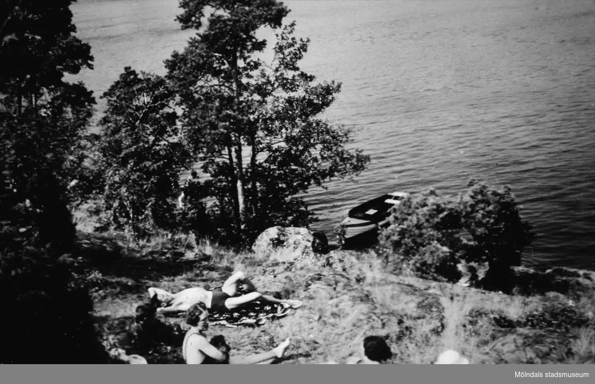 Några personer ligger och solar på en bergssluttning, troligtvis vid Tulebosjön cirka 1930. Mannen i mitten som ligger på en filt är "Tulebos starke man" Karl Alberts. I sjön ligger en fastbunden eka.