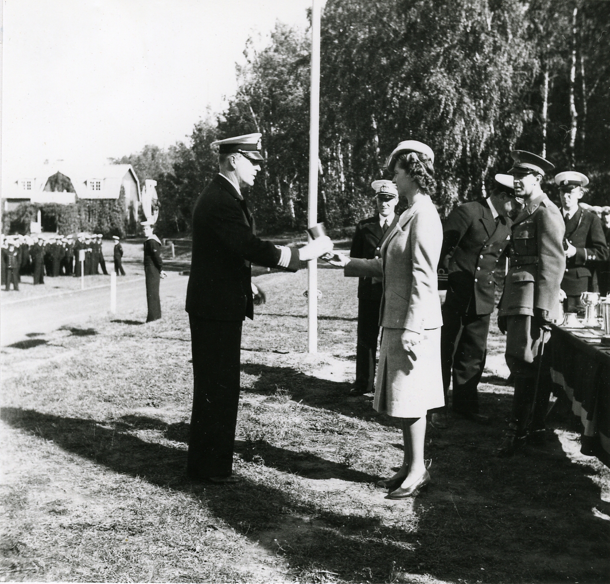 Prisutdelning vid Kustflottans idrottstävlingar på Hårsfjärdens idrottsplats.
Prinsessan Sibylla överlämnar pris till en kommendörkapten. I bakgrunden Prins Gustav Adolf.