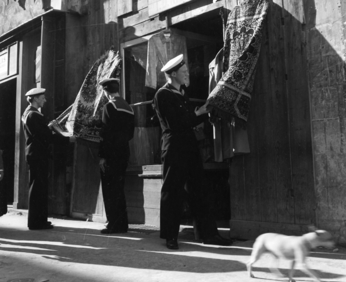 [från Fotobeskrivning:] [---] "Besättningsmän från kryssaren Fylgia utanför en butik i utländsk hamn. Foto troligen från långresan i Medelhavet och Väst-Afrika åren 1947-48."