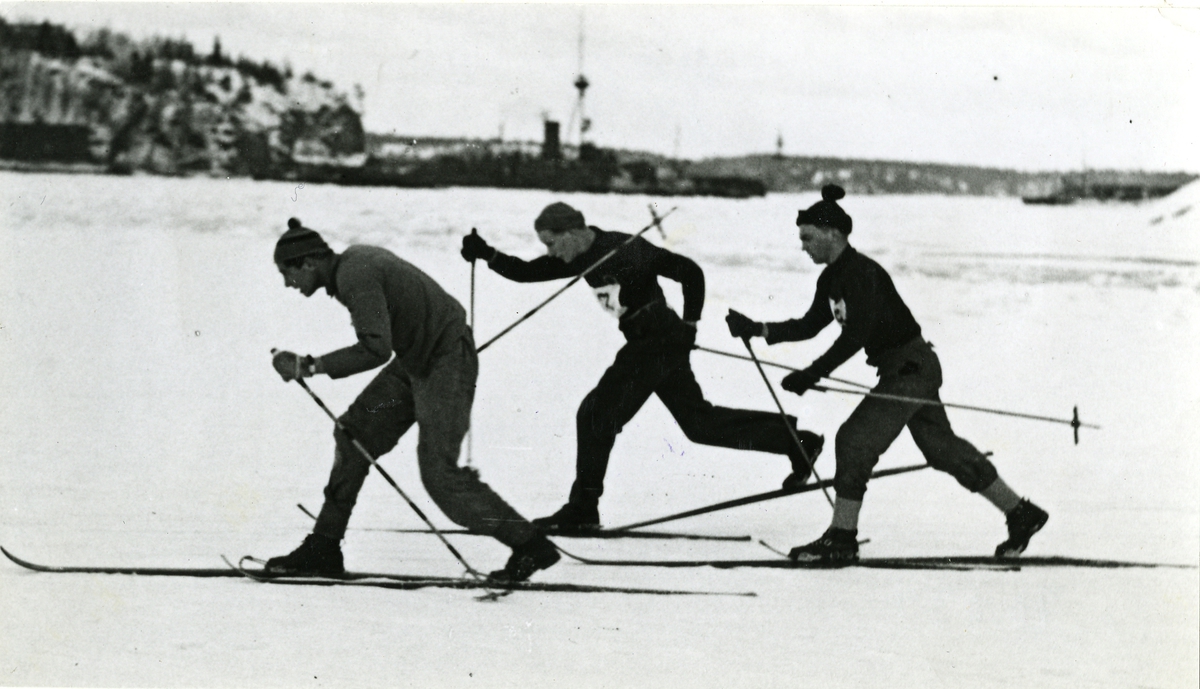 Tre man skidar på isen. Första start i 3-milsloppet på skidor vid Hårsfjärden den 13 mars 1941.