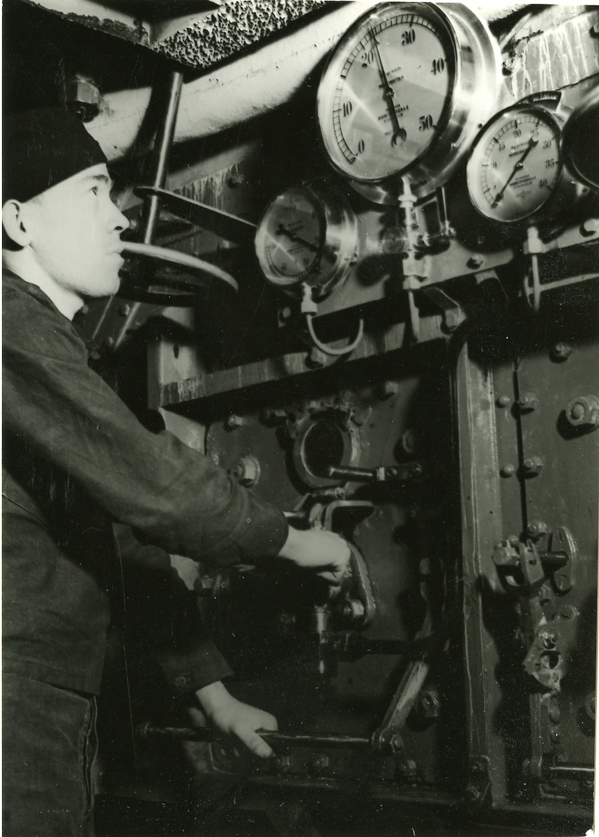 Besättningsman kontrollerar tryckmätare i maskinrummet.