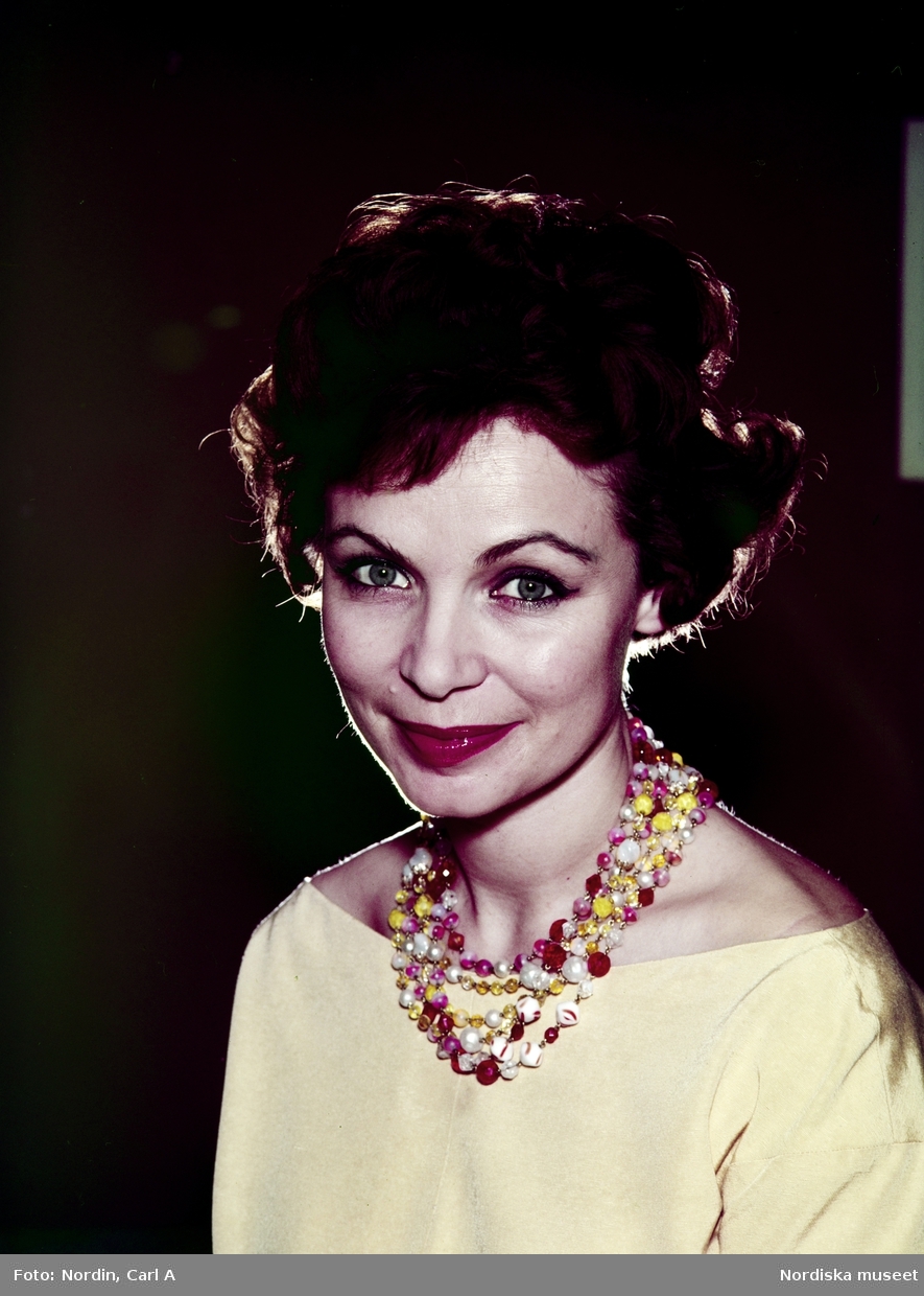 Kvinna i gul överdel och flerfärgat halsband.