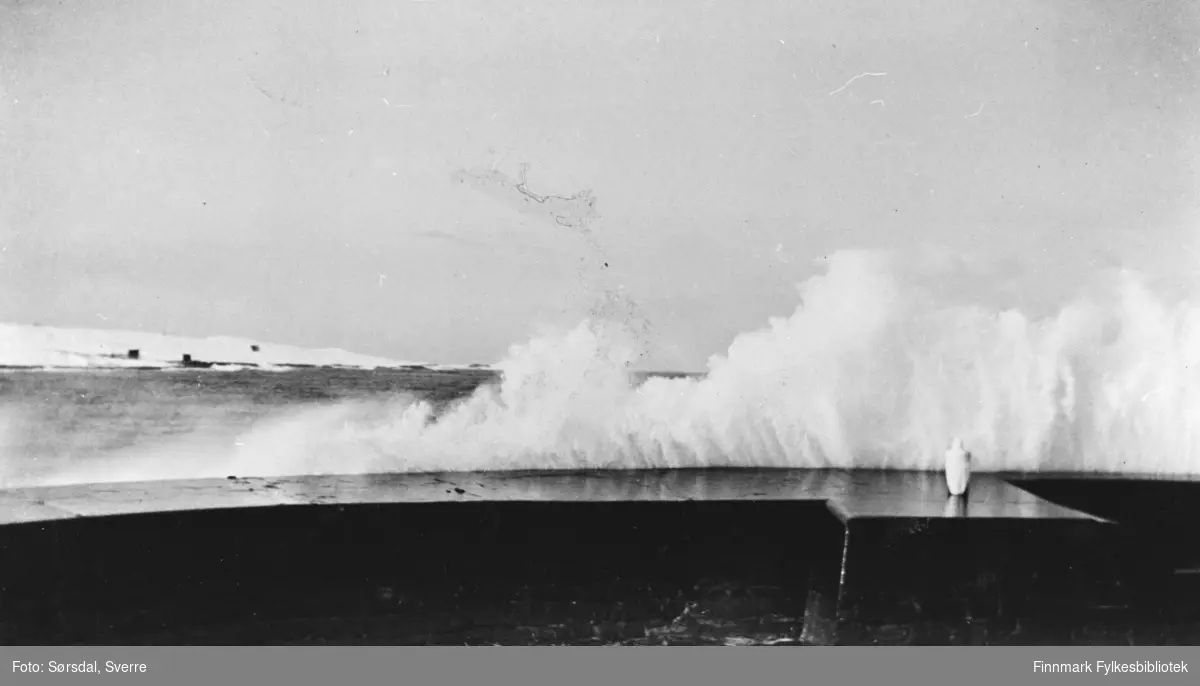 Bildet av bølger som bryter over moloen.
