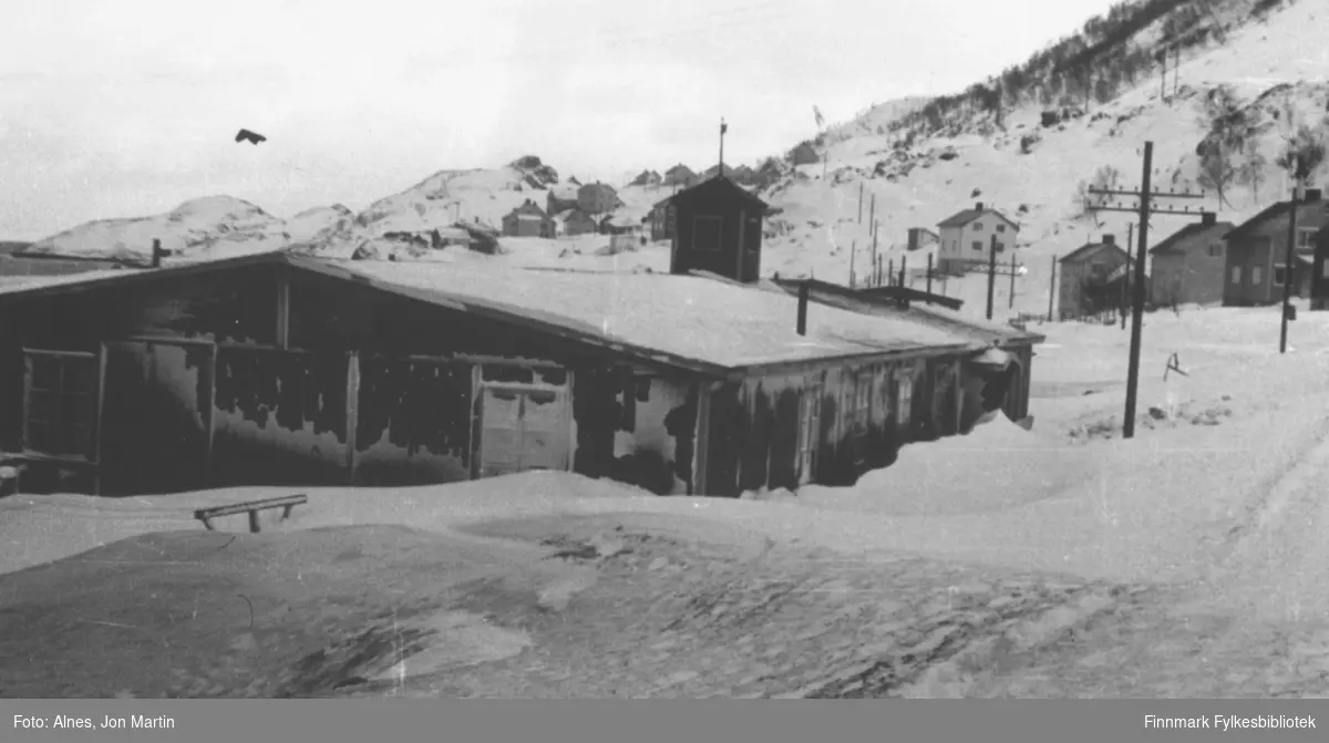 Øksfjord fotografert utover mot Hankenbakken i 1953. I forgrunnen den gamle kirkebrakka, som også ble brukt som skolehus etter krigen. Brakka sto mellom der Coop Øksfjord og Øksfjord bilservice er i dag (2006)