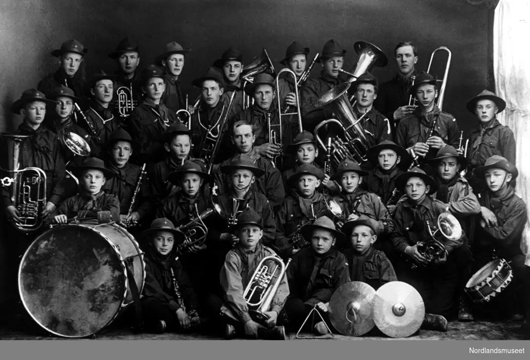 Musikkorps, 33 speidergutter med div. instrumenter. Bl.a. stortromme, liten tromme, symbaler, baryton, bass, fløyte, kornett, horn, trombone og triangel.