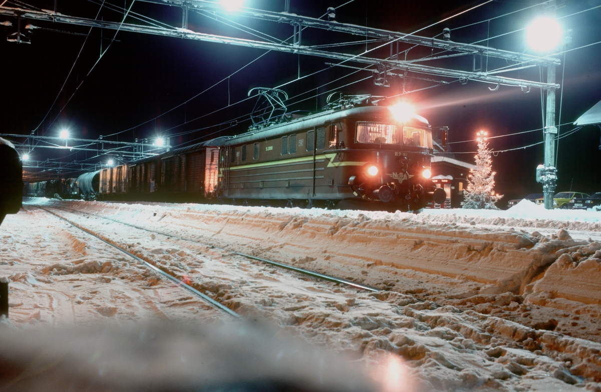Julekort stemning i Eina stasjon. NSB godstog 5164, Gjøvik - Alnabru, står klar til avgang med elektrisk lokomotiv El 11 2090.